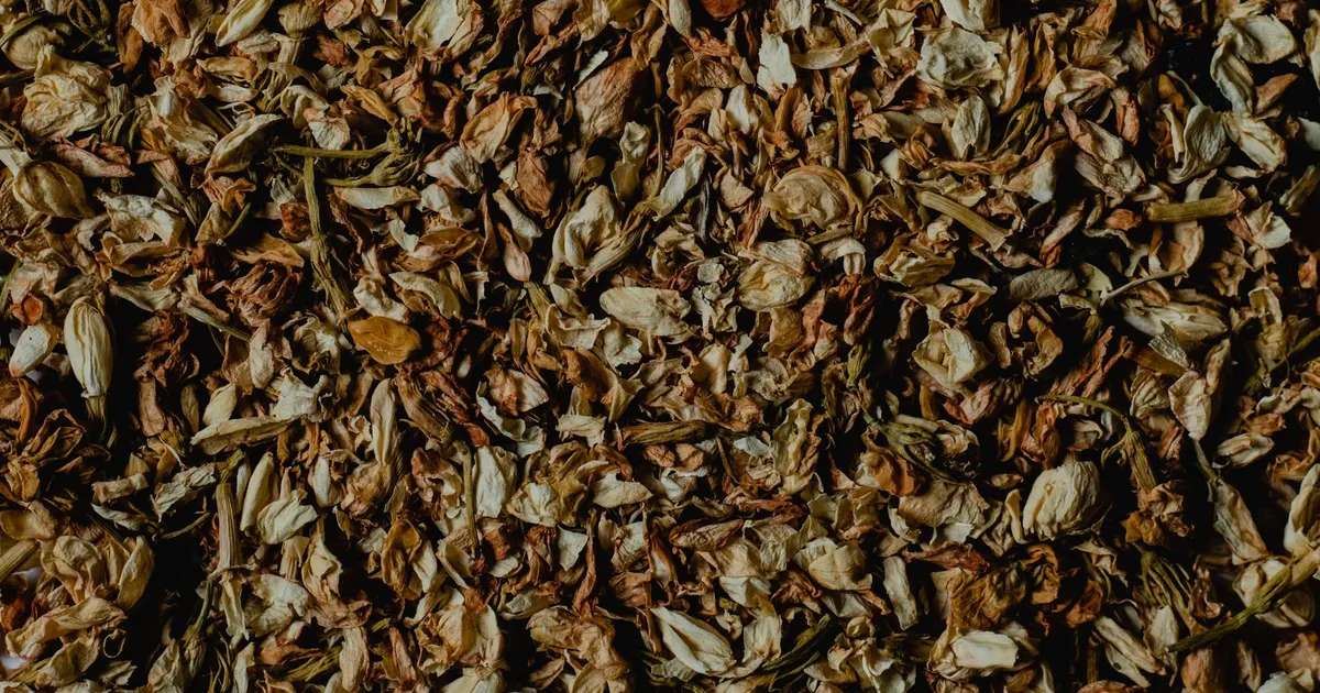 Close-up of dried jasmine flowers mixed with tea leaf, showing the texture of jasmine tea after scenting
